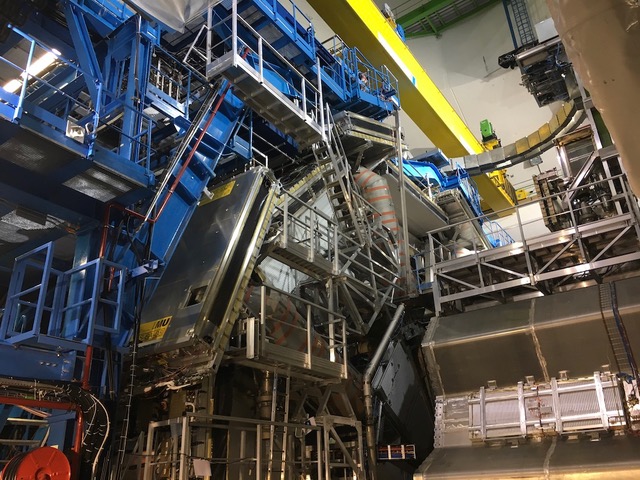 Picture of the ATLAS detector, many steel plates and particle detector elements are shown inside of a cavern with concrete walls. The detector is surrounded with blue ladders and platforms of steel.