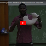 screenshot of the YouTube video preview of Ben Otange's Slam at the 1st PIER science slam showing a young man holding up a travel pillow in front of a blackboard with nonsensical formulas
