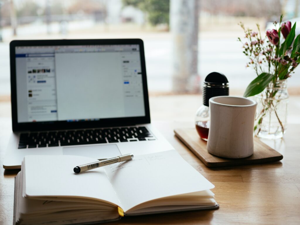 Image showing different items on a desk, including laptop, notebook, pen, and home accessories. 