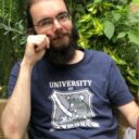 Benoît seated in garden wearing a T-shirt reading "University of Laziness"