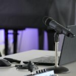 Desk with open laptop and microphone on a stand